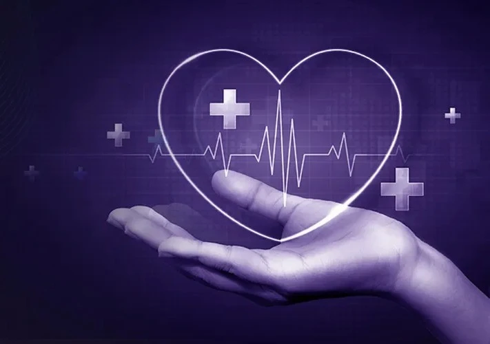 Hand holding a glowing heart outline with medical symbols and an ECG line, representing IT solutions for healthcare that support accurate, compliant, and data-driven clinical systems.